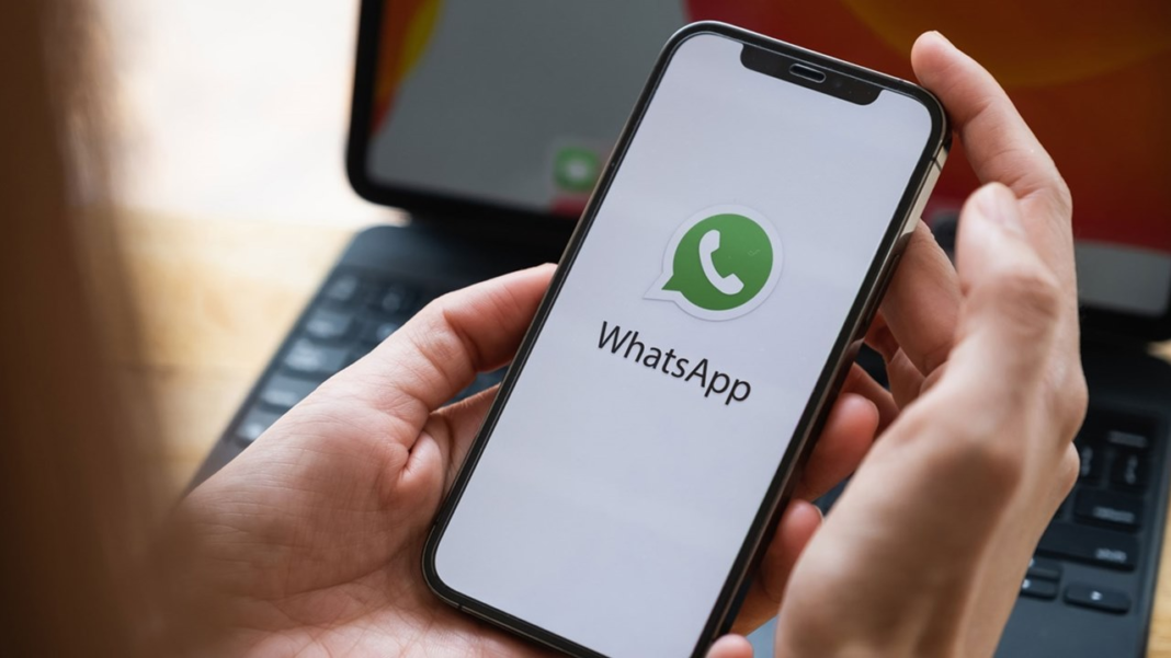Persona sosteniendo un teléfono móvil con el logotipo de WhatsApp en la pantalla